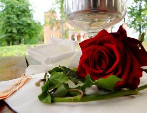 a red rose sitting on a table next to a wine glass at Hotel Zamek Karnity in Miłomłyn