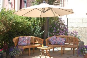 two benches with pillows sitting under an umbrella at Warwick House in Penzance