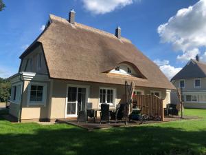 Casa con techo de paja, mesa y sillas en Grüne Hufe en Born