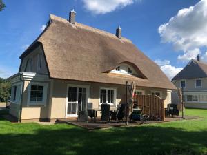 a house with a thatched roof with a table and chairs at Grüne Hufe in Born