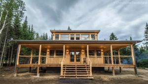 een groot houten huis met een grote veranda bij Chalet TAO par Les Chalets Spa Canada in La Malbaie