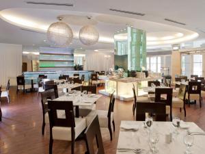 un restaurante con mesas blancas, sillas y luces en Silka Maytower Kuala Lumpur en Kuala Lumpur