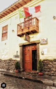 a building with a balcony with flags on it at OkiDoki Cusco Hostal in Cusco