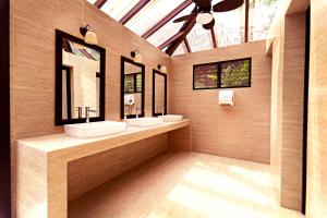 a bathroom with two sinks and two mirrors at Jungle Lodge Tikal Hostal in Tikal