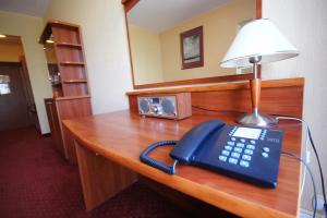 a desk with a phone and a lamp on it at Hotel Aros in Tychy