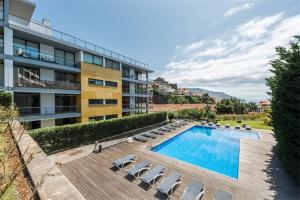 un immeuble d'appartements avec une piscine et des chaises longues dans l'établissement Casas do Forte do Pico, à Funchal