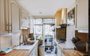 uma pequena cozinha com armários brancos e um lavatório em Double room in Marylebone em Londres