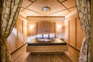 - une chambre avec un lit dans une pièce dotée de murs en bois dans l'établissement Landhotel Denggerhof, à Mayrhofen