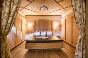 1 dormitorio con 1 cama en una habitación con paredes de madera en Landhotel Denggerhof, en Mayrhofen
