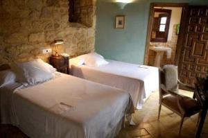 a hotel room with two beds and a table at Hospedería del Monasterio in Osuna