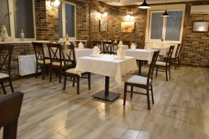 a dining room with white tables and chairs and brick walls at Три Сімки in Vyshhorod