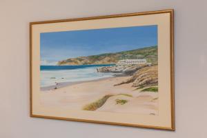 a framed painting of a beach with a house at Charming Paddington in London