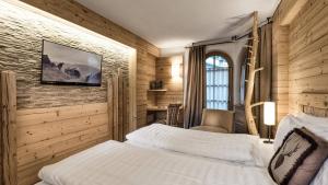 a bedroom with a bed and a tv on a wall at Sporthotel Romantic Plaza in Madonna di Campiglio