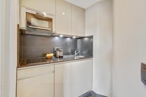 - une cuisine avec des placards blancs et un évier dans l'établissement Luxury Apartment Paris Louvre, à Paris
