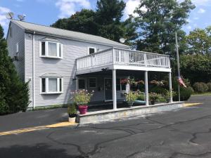 a white house with a porch and a balcony at Atlantic Motel in East Wareham