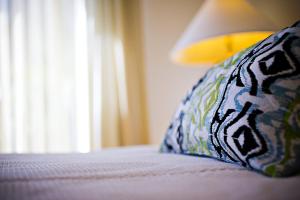 a close up of a bed with a pillow and a window at Stay in Tamarindo Condominiums in Tamarindo