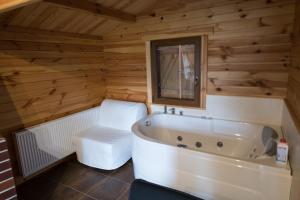 a bathroom with a white tub in a wooden room at Domki Luksusowe Eskada in Ustronie Morskie