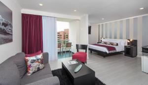 Habitación de hotel con cama y sala de estar. en The Morgana Poblado Suites Hotel, en Medellín