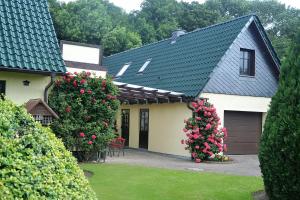 a house with two flowering bushes and a garage at Ferienwohnung 1 bei Familie Saupe in Schaprode