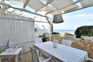 - une table et des chaises blanches sur une terrasse donnant sur l'océan dans l'établissement Casa Mare Holiday Pozzallo, à Pozzallo