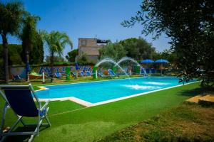 a large swimming pool with lawn chairs and umbrellas at Paradise beb in Giovinazzo