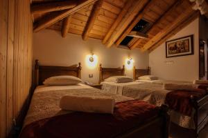 three beds in a room with wooden ceilings at Hotel Kastro in Gjirokastër