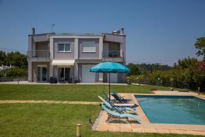 una casa con piscina con sillas y sombrilla en Deep Purple House 2, en Kriopigi