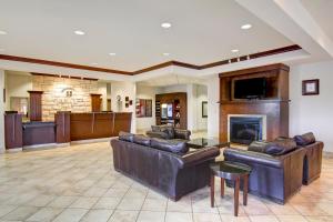 a living room with leather furniture and a fireplace at Canalta Hotel Weyburn in Weyburn