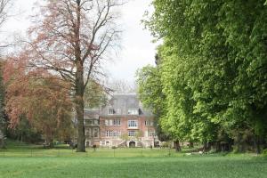 a large house in the middle of a field with trees at Studio du Valvion in Beauquesne