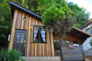 una casa pequeña con una puerta negra y un árbol en Loft & Log House, en Okayama