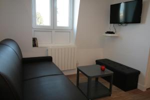 a living room with a couch and a table and a tv at Comme à la Maison - DE LA TOUR in Saint-Quentin