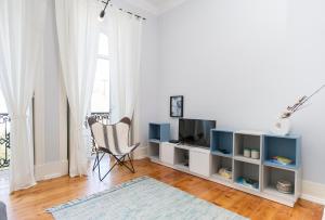 a white living room with a tv and a chair at Lisbon Dreams Estrela TOP Suites in Lisbon