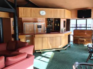a room with a bar with a couch and a piano at The Village Inn Hotel in Te Anau