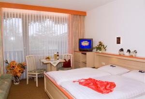 a bedroom with a bed and a tv and a table at Hotel am See in Neubäu