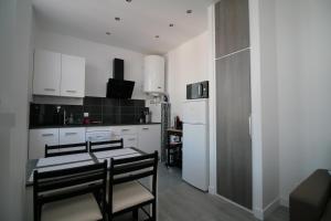 a kitchen with white cabinets and a table and chairs at Comme à la Maison - CENTRE-VILLE in Saint-Quentin