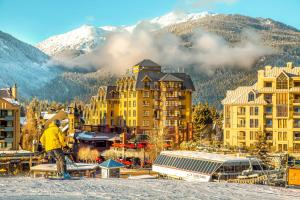 a man is standing on a snowboard in front of a resort at Sundial Hotel in Whistler
