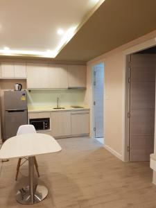 a kitchen with white cabinets and a table in it at Seven Seas Jomtien Dream in Jomtien Beach
