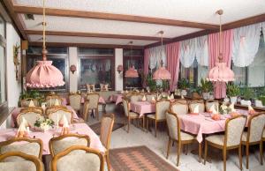 a restaurant with pink tables and chairs and pink chandeliers at Hotel am See in Neubäu