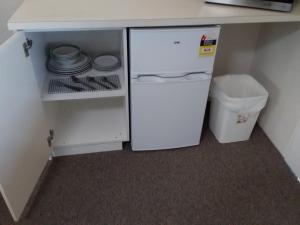 a small kitchen with a white refrigerator and a trash can at Green Door Motel in Albury