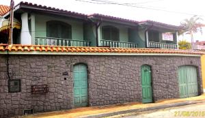 a building with green doors and a stone wall at Suítes Casa Verde in Arraial do Cabo