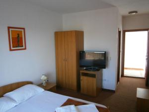 a hotel room with a bed and a television at Guest House Babić in Neum