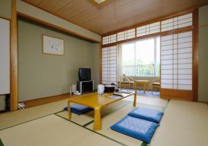 ein Wohnzimmer mit Couchtisch und ein Zimmer mit Fenster in der Unterkunft Kyukamura Ohkunoshima in Takehara