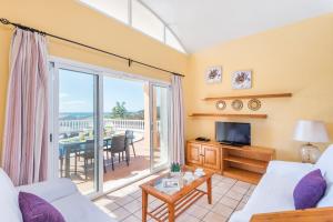 sala de estar con sofá, TV y balcón en Villa Elena - Son Bou, en Son Bou