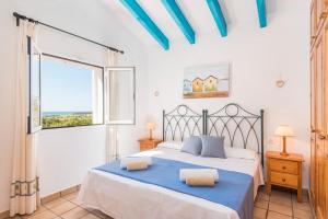 Un dormitorio con una cama con sábanas azules y una ventana. en Villa Elena - Son Bou, en Son Bou 20 fotos más