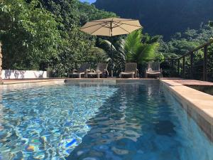 a swimming pool with chairs and an umbrella at La Villa Te Fetia Nui Moorea in Teavaro