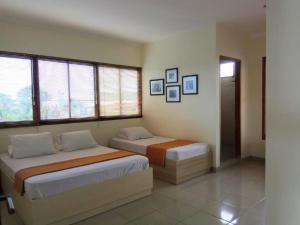 1 dormitorio con 2 camas en una habitación con ventanas en GK Gallery Rumah Sewa, en Purwokerto