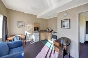 uma sala de estar com um sofá azul e uma cozinha em Garden Motel em Dunedin