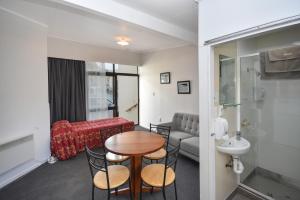 Habitación con mesa, sillas y baño. en Garden Motel, en Dunedin