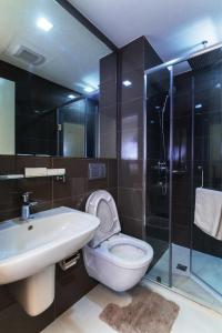 a bathroom with a toilet and a sink and a shower at Oasis Regency @ Acqua Livingstone near Rockwell in Manila