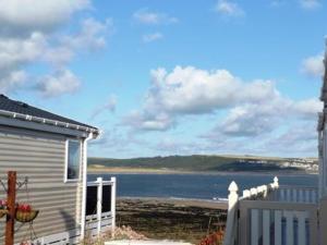 une maison avec une clôture et une vue sur l'eau dans l'établissement Caravan by the sea Trecco Bay, à Porthcawl